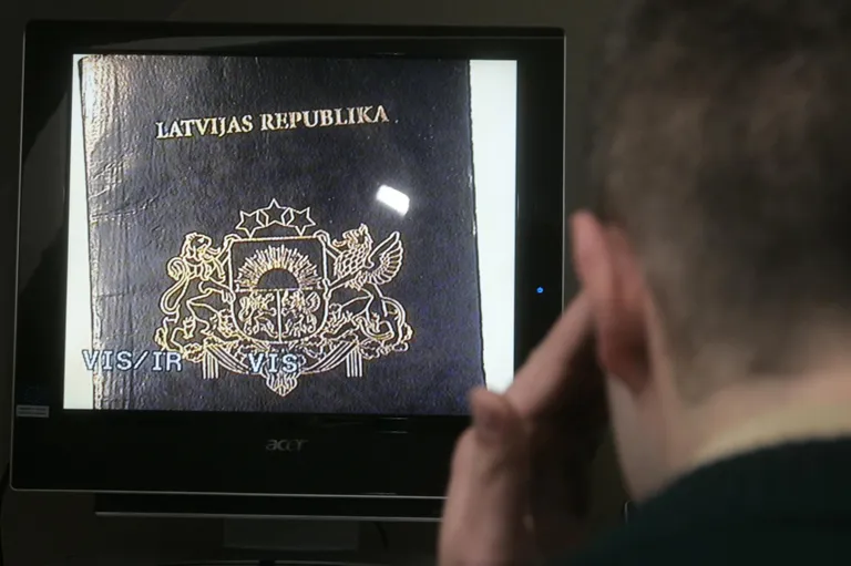 Пограничник проверяет латвийский паспорт.