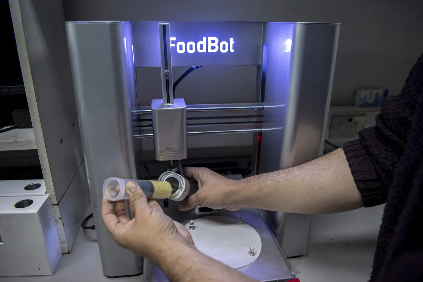 Food engineering student Marcelo Beltran shows how to load food in a 3D printer at the lab of Chile's University in Santiago, on June 17, 2022. - Dehydrated cochayuyo seaweed (Durvillaea antarctica) (a large species of southern bull kelp), instant mashed potatoes and hot water are the necessary ingredients for the nutritious menu of 3D printed food that is seeking to revolutionize the food market, mainly aimed at children, in Chile. (Photo by Martin BERNETTI / AFP)