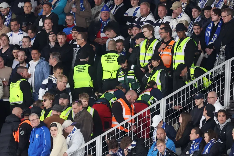 Turvatöötajad Helsingi Olümpiastaadionil tribüünil, kus arstid osutavad esmaaabi pealtvaatajale.