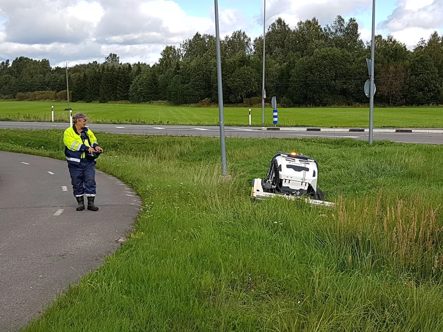 Taristoni tehnik Tarmo Nadel juhib puldist robotniidukit, mis kraaviperved kenasti rohust lagedaks niidab.
