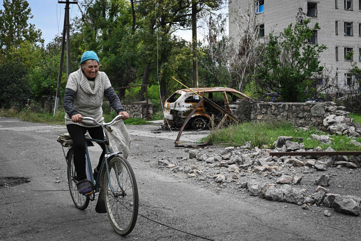 Naine sõidab hiljuti vabastatud Võsokopillja külas jalgrattal mööda rängalt lahingutes kannatada saanud kohalikust haiglast.