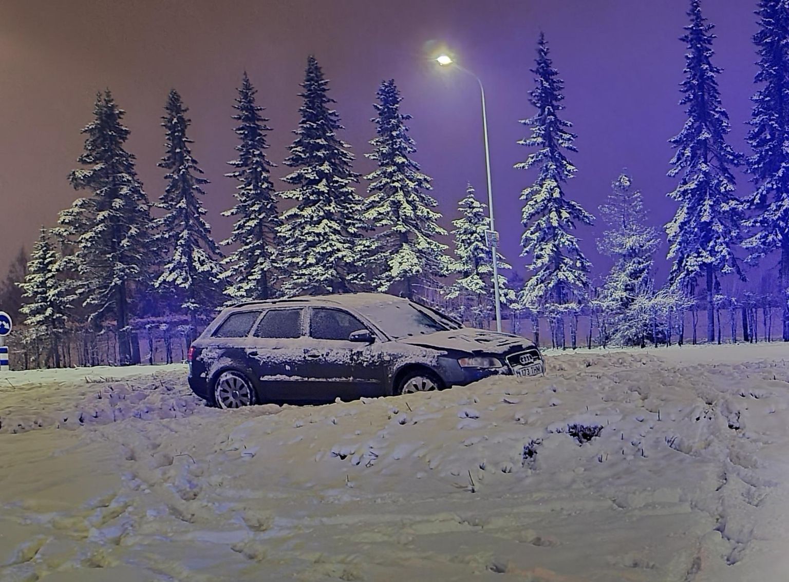Auto jäi pidama ringristmiku lumisel haljasalal.