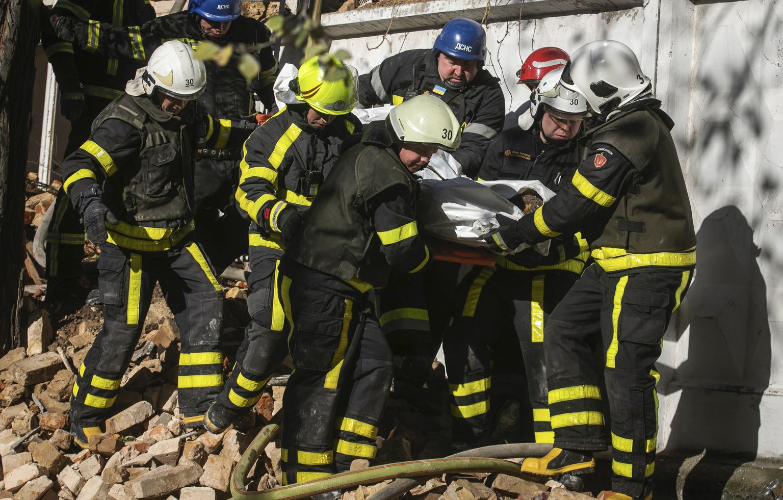 Спасатели несут тело человека, погибшего в результате обстрела зданий беспилотником в Киеве.