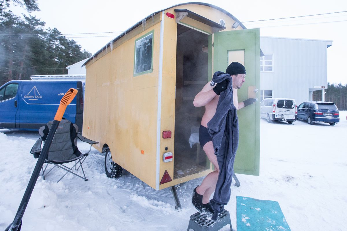 Марко выходит из бани на прицепе, дополняющей установленную на льду баню-палатку и баню спортцентра.