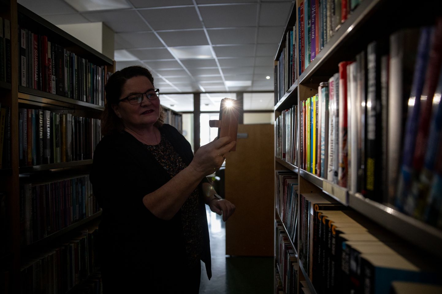 Lagedi raamatukogu direktor Tea Sõlg taskulambi valgel raamatut otsimas.