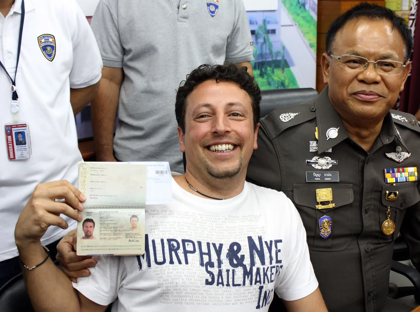 Italian Luigi Maraldi, left, whose stolen passport was used by a passenger boarding a missing Malaysian airliner, shows his passport as he reports himself to Thai police Lt. Gen. Panya Mamen, right, at Phuket police station in Phuket province, southern Thailand Sunday, March 9, 2014.   Maraldi spoke at a police news conference in the Thai resort of Phuket, where he showed his current passport, which replaced the stolen one, and expressed surprise that anyone could use his old one.  (AP Photo/Krissada Muanhawang) / TT / kod 436