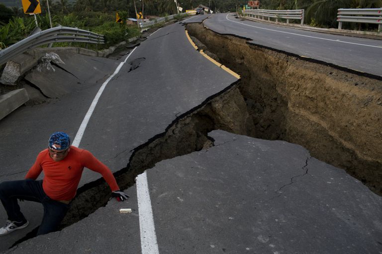 A man jokes around after taking some pictures of a section of highway that collapsed due to a 7.8-magnitude earthquake, in Chacras, Ecuador, Tuesday, April 19, 2016. The strongest earthquake to hit Ecuador in decades flattened buildings and buckled highways along its Pacific coast, sending the Andean nation into a state of emergency. (AP Photo/Rodrigo Abd)