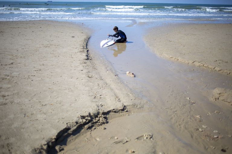 Surfaja puhastab Vahemere rannal naftaseks saanud surfilauda Iisraeli Gadori looduskaitsealal Hadera lähistel. 