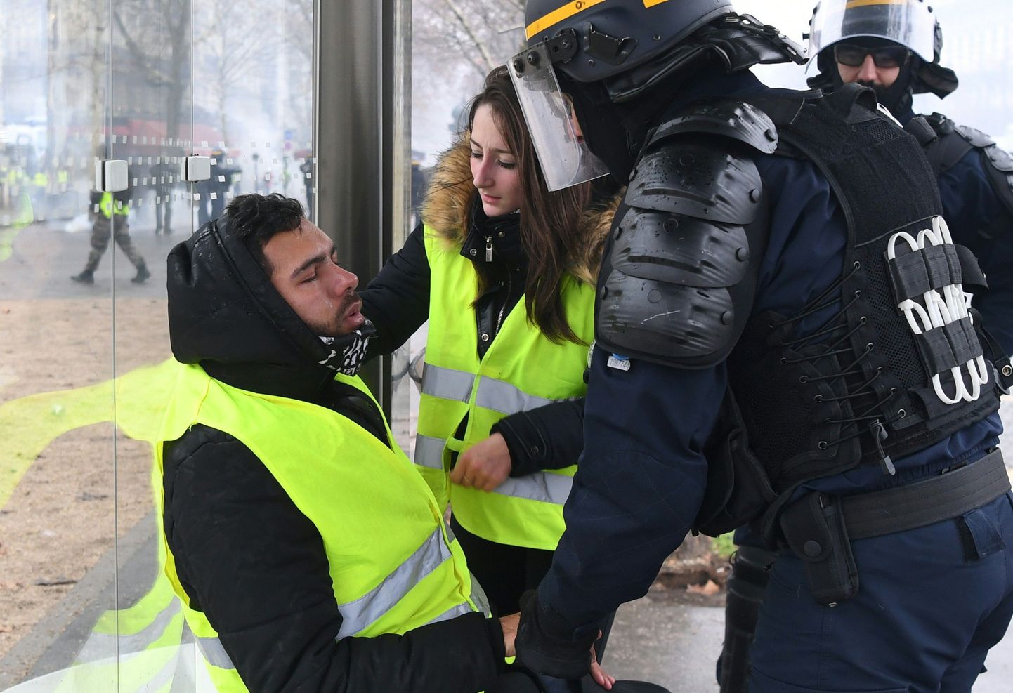 Policists un sabiedriskā aktīviste sniedz palīdzību vīrietim, kas cietis no asaru gāzes