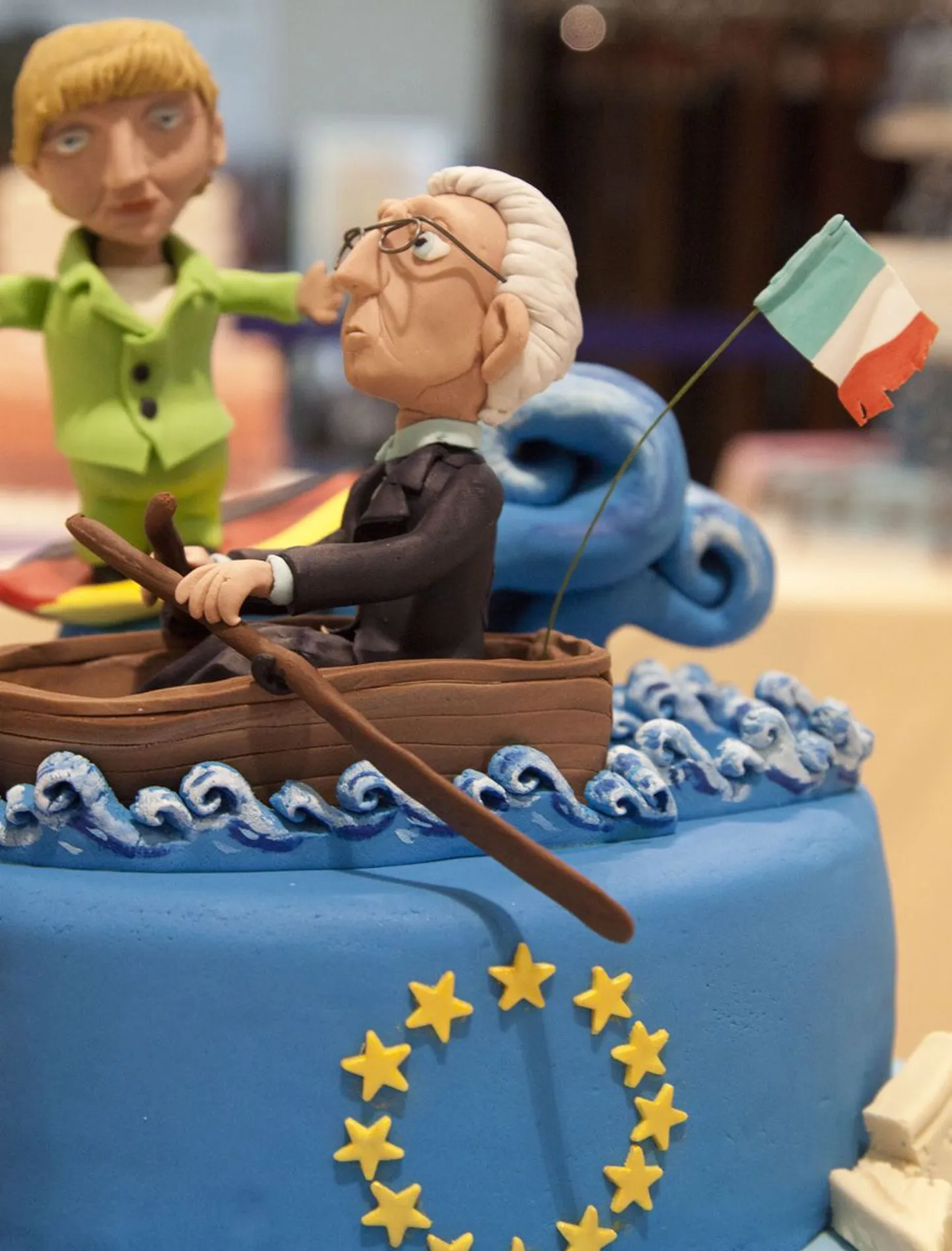Itaalia peaministrit Mario Montit kujutav figuur sinisel eurotordil Napolis šokolaaditoodete näitusel ülemöödunud kuul, taamal paistmas samuti torti kaunistanud Saksa kantseri Angela Merkeli kujuke.