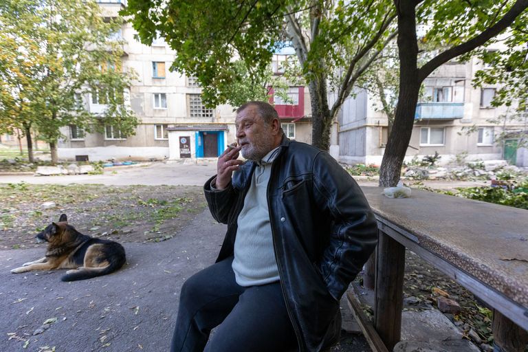 Шахтер на пенсии, лишившийся квартиры и всего нажитого имущества после попадания российской ракеты, сидит на скамейке перед своим бывшим домом.