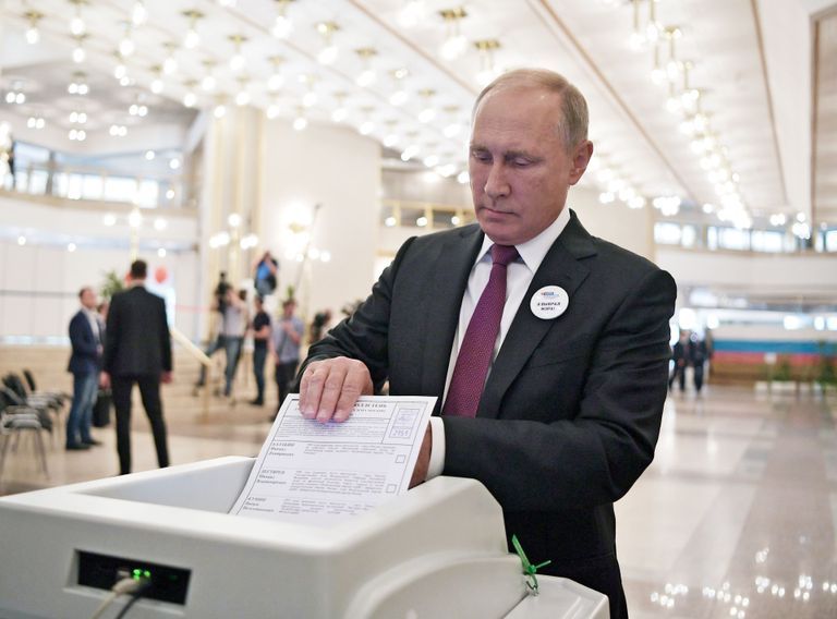Владимир Путин опускает бюллетень для голосования в урну на одном из избирательных участков Москвы, 2018 год.