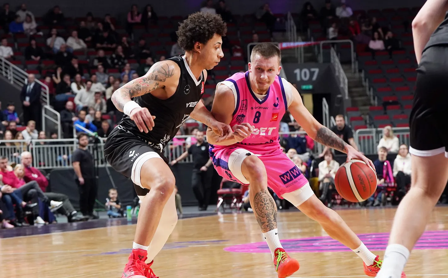 ''VEF Rīga'' basketbolists Isufs Sanons (nr.30, melnā tērpā) un "Rīgas zeļļi" spēlētājs Roberts Bērziņš (nr.8, rozā tērpā)