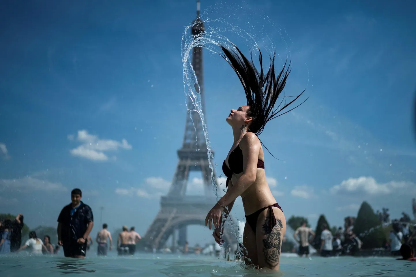 Palavus piinab, kuumus kurnab. Pikajuukseline naine jahutamas end Pariisis Trocadero purskkaevus kuulsa Eiffeli torni taustal.