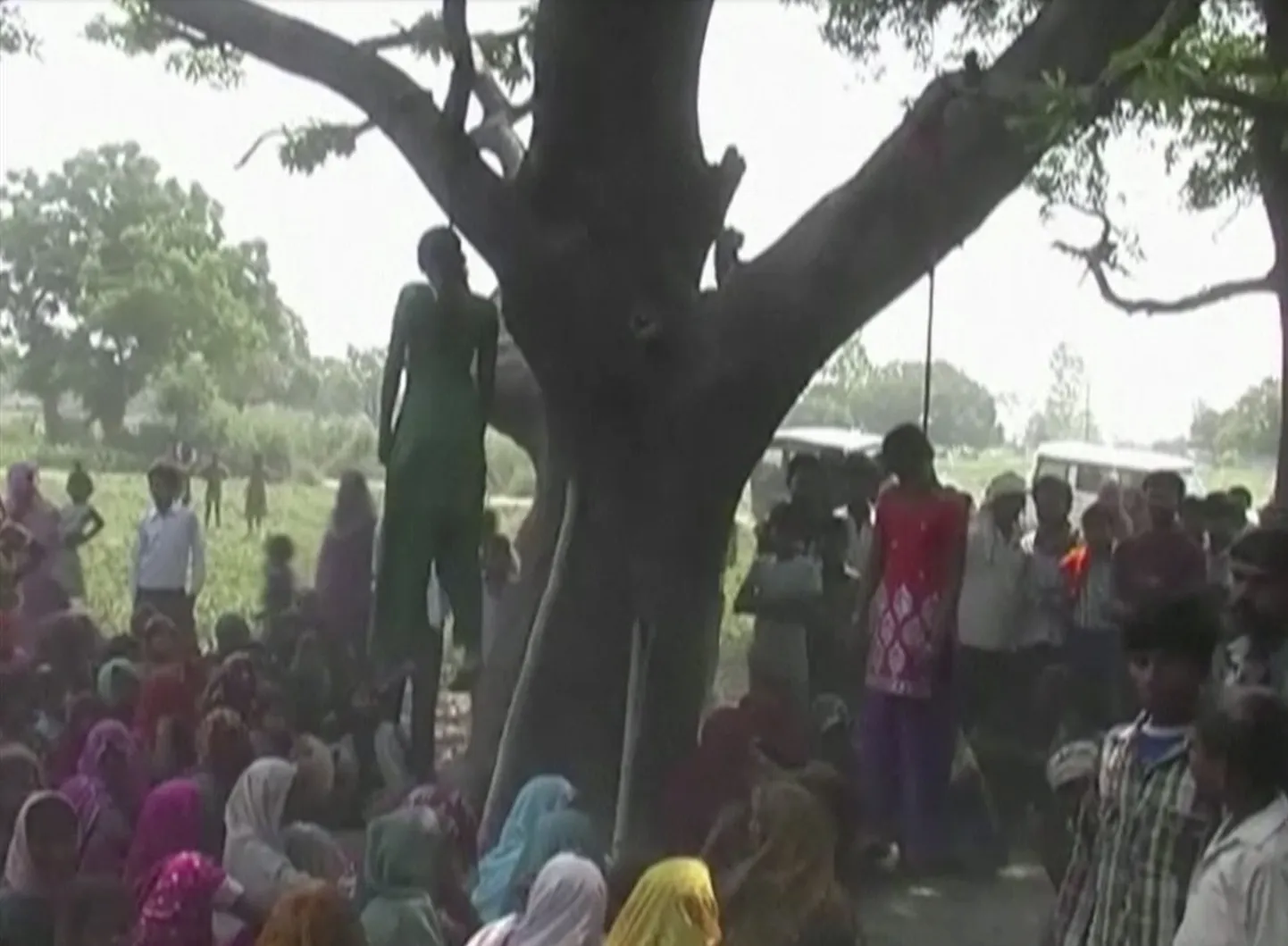 India Katra külaelanikud istumas kahe üles poodud õe juures. Kolm meest, sealhulgas kaks politseinikku, vägistasid tüdrukud ja seejärel poosid nad üles.