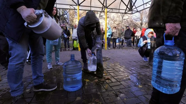 Грурра людей с пластиковыми бутылками набирает воду из колонки.