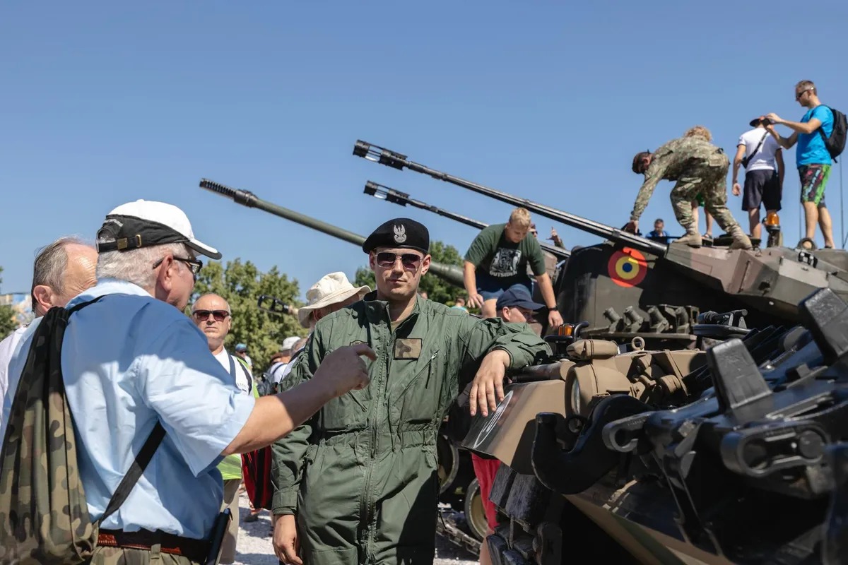 A Polish soldier showcasing a vehicle at a military picnic.