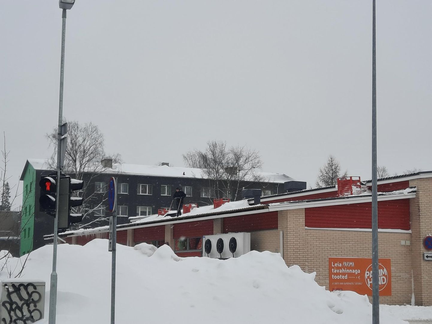 Turvavarustuseta töömees Rakvere Rimi katuselt lund lükkamas.