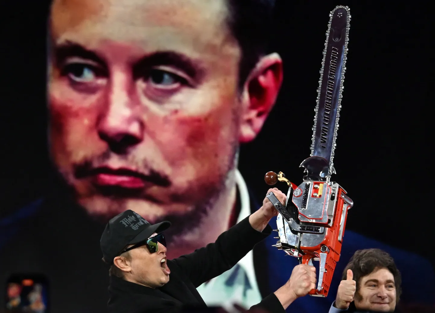 Elon Musk 21. veebruaril 2025 Marylandis Oxen Hillis konservatiivset poliitilise tegevuse konverentsil (CPAC) näitamas mootorsaagi, mille talle kinkis Argentina president Javier Millei (kõrval)