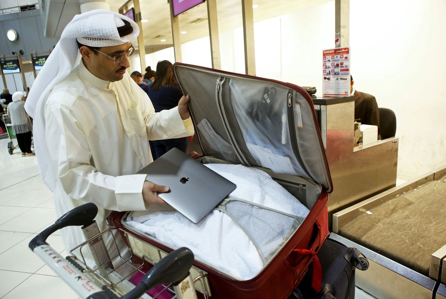 USAsse lendav Kuveidi sotsiaalmeedia aktivist Thamer al-Dakheel Bourashed paneb oma sülearvuti äraantavasse pagasisse Kuveidi rahvusvahelises lennujaamas 23. märtsil, vahetult pärast USA keelu kehtestamist.