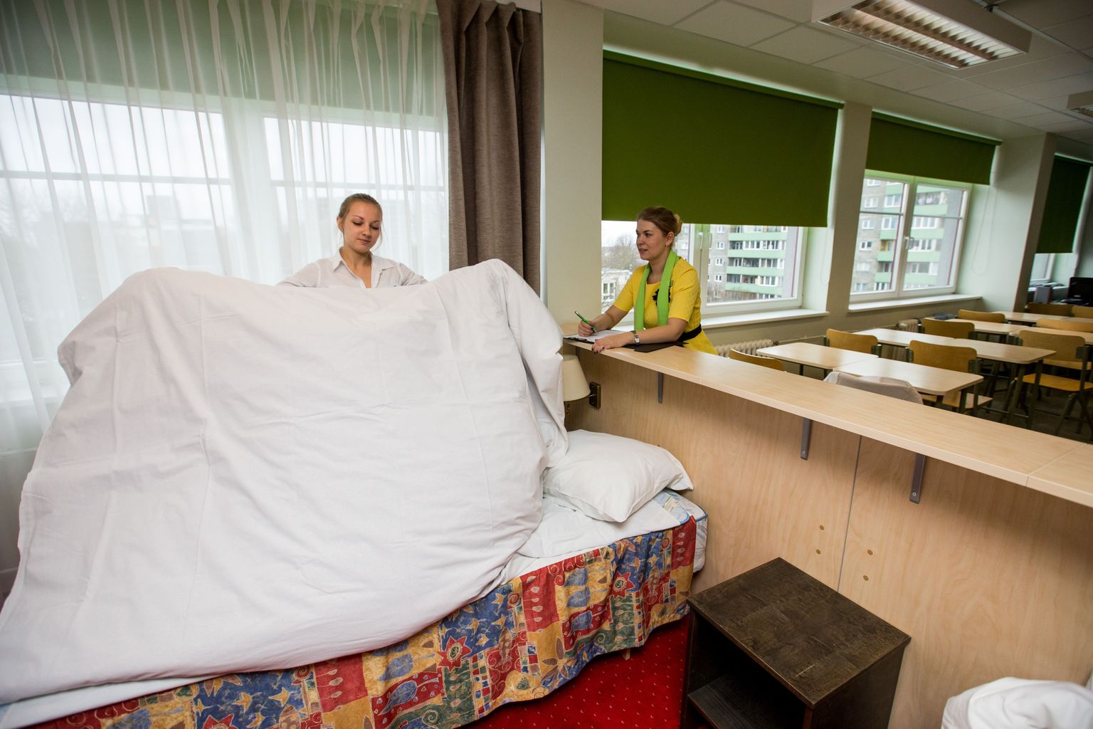 Tallinna Teeninduskooli õpperuumis on sisse seatud voodiga hotelliruum: õpilane Kadi Saar ja majutuserialade juhtivõpetaja Kristi Leinus.