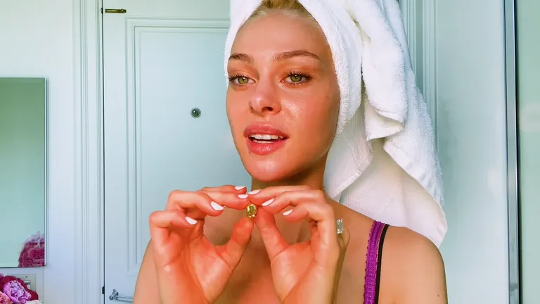 Nicola Peltz näitamas Brooklyni hammast, mida kannab kaelas.