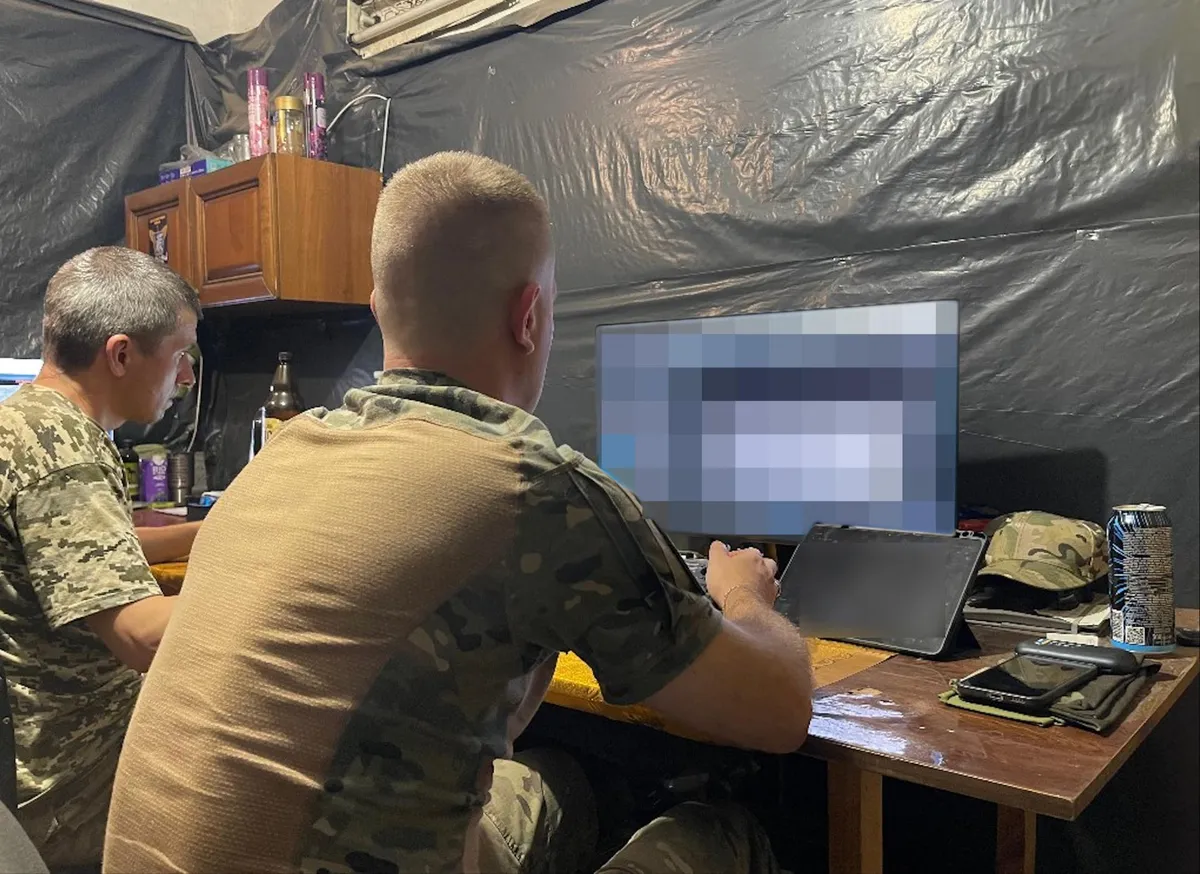 Drone pilot Oleksandr at the control point away from the front line. His assistant sits on the left. Energy drinks are the drone operator's best friends.