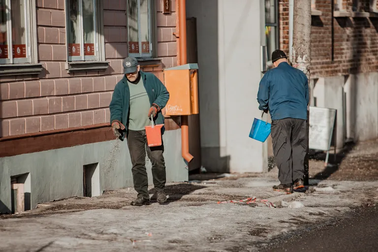 Mehed puistavad libedale kergliiklusteele soola.