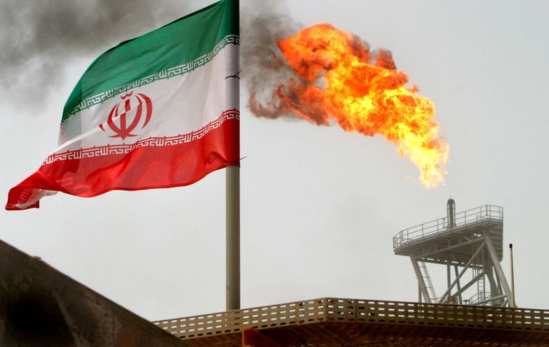 Газовый факел на нефтедобывающей платформе рядом с иранским флагом в Персидском заливе, 2005 год.