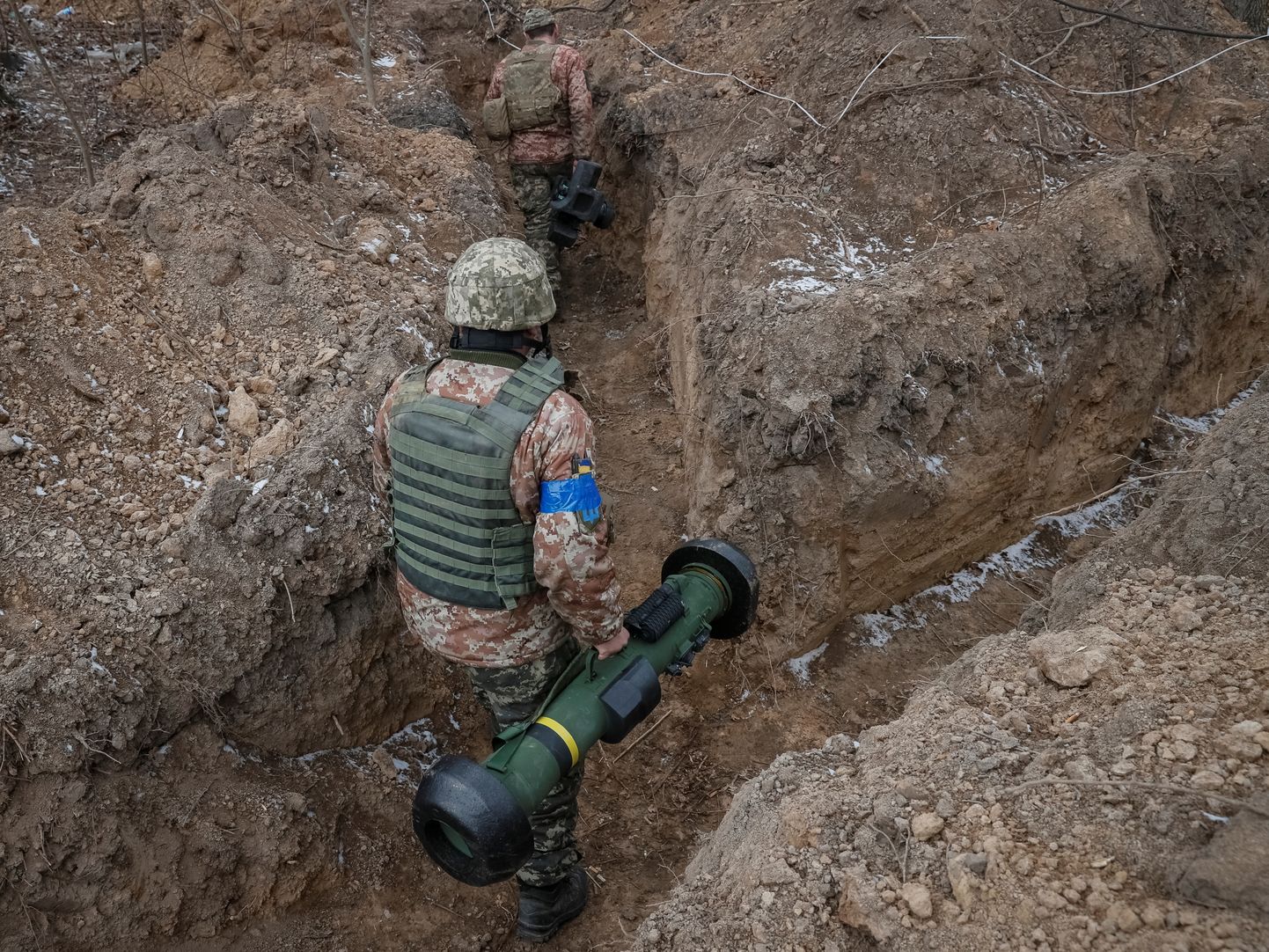 A Ukrainian service member walks along a trench with a Javelin missile system at a position on the front line.