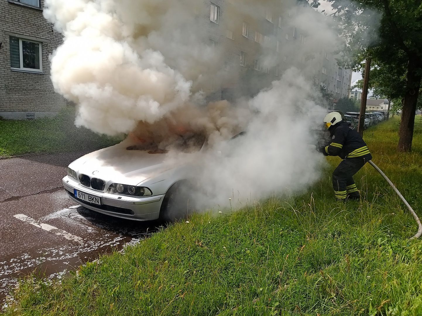 Спасатель тушит загоревшийся в Нарве автомобиль BMW.