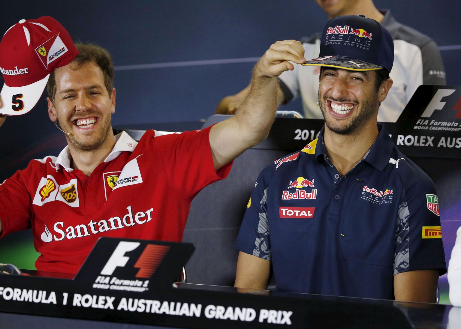 Formula One -  Australia Grand Prix - Melbourne, Australia - 17/03/16 - Ferrari F1 driver Sebastian Vettel (L) replaces the hat of Red Bull Racing F1 driver Daniel Ricciardo after placing his own Ferrari hat on Ricciardo's head in response to a question on whether Ricciardo will move to Ferrari in 2017 during a news conference at the Australian Formula One Grand Prix in Melbourne. REUTERS/Brandon Malone