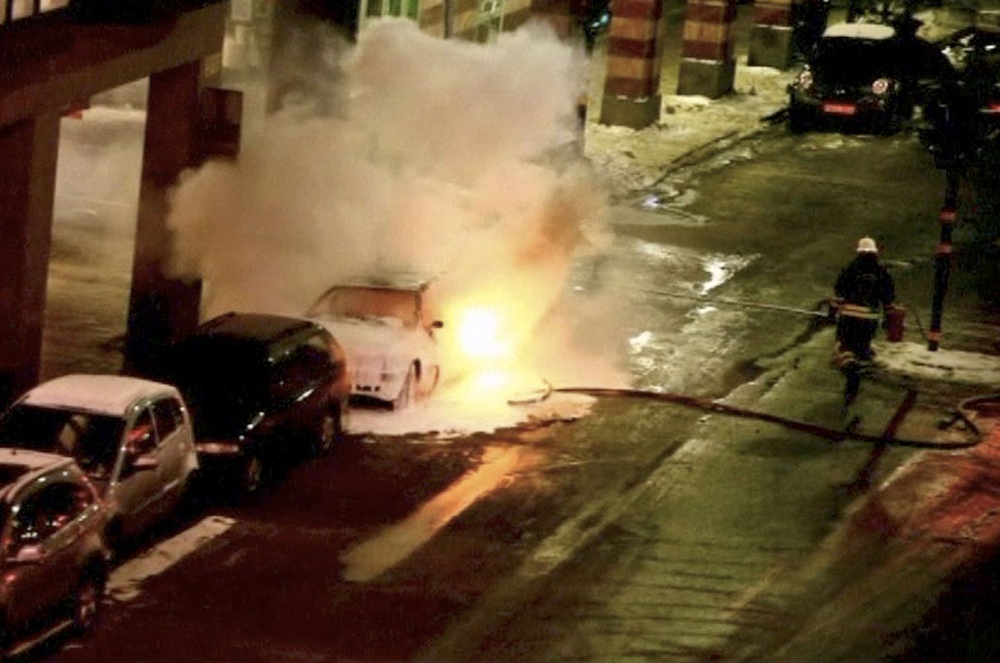 Tuletõrjuja kustutab Stockholmi kesklinnas süttinud sõiduautot.