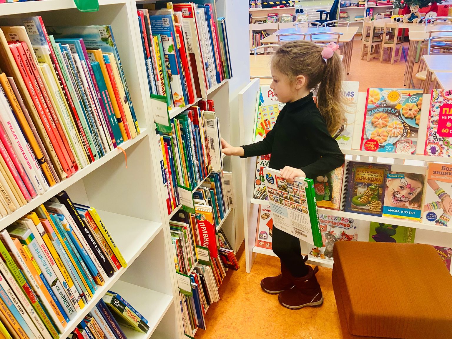 Ребенок в библиотеке выбирает книги.
