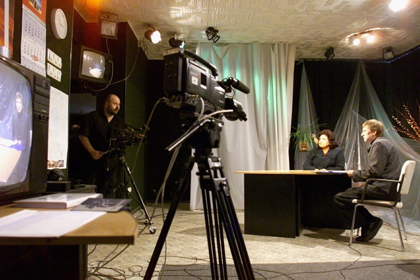 Kui ALO-TV tegi veel jutusaateid, oli üks neist «Tartust Tartumaale». 8. aprillil 2001 jäid stuudios pildile Jaan Kalmus (kaamera taga), Tartu linnavalitsuse noorsooteenistuse juhataja Luule Press ning saatejuht ja toimetaja Kalle Hein.
