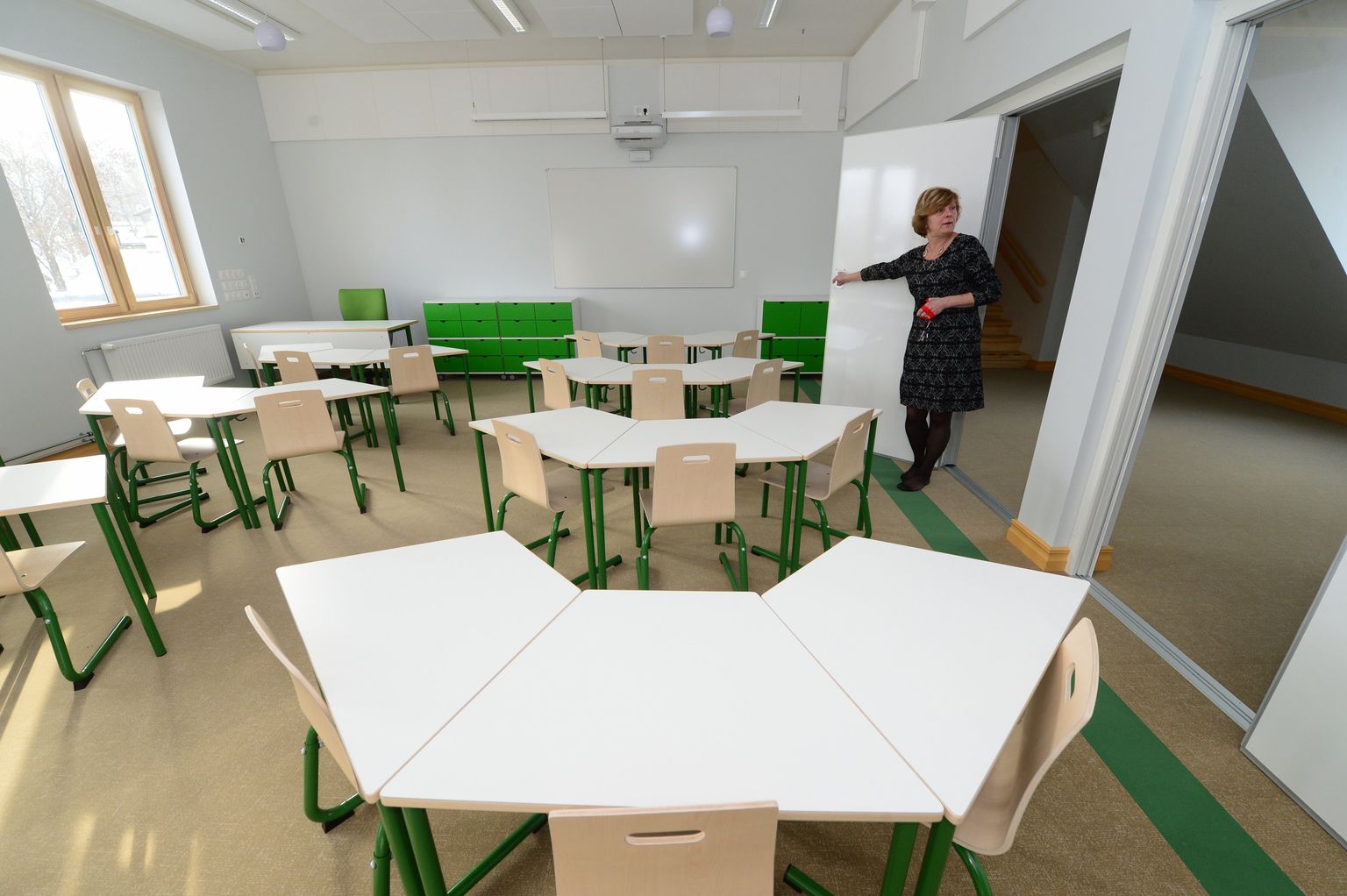 Tartu Kesklinna kooli direktor Kersti Vilson näitab, kuidas uue klassiruumi seinu saab vajadust mööda voltida.