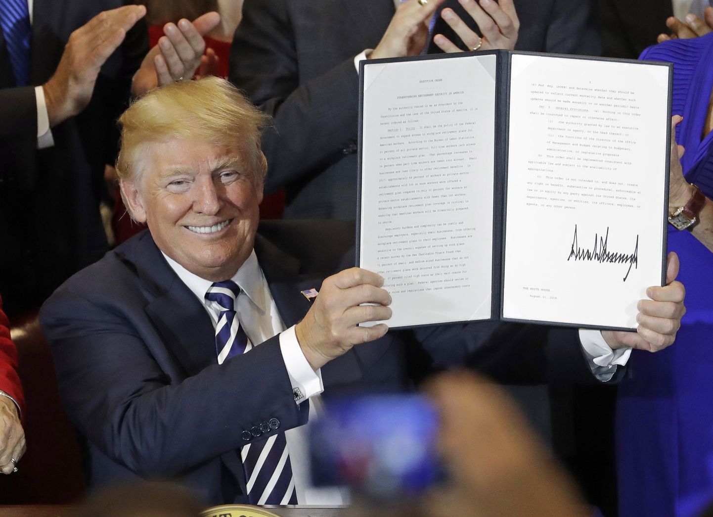 USA president Donald Trump allkirjastatud dokumenti käes hoidmas.