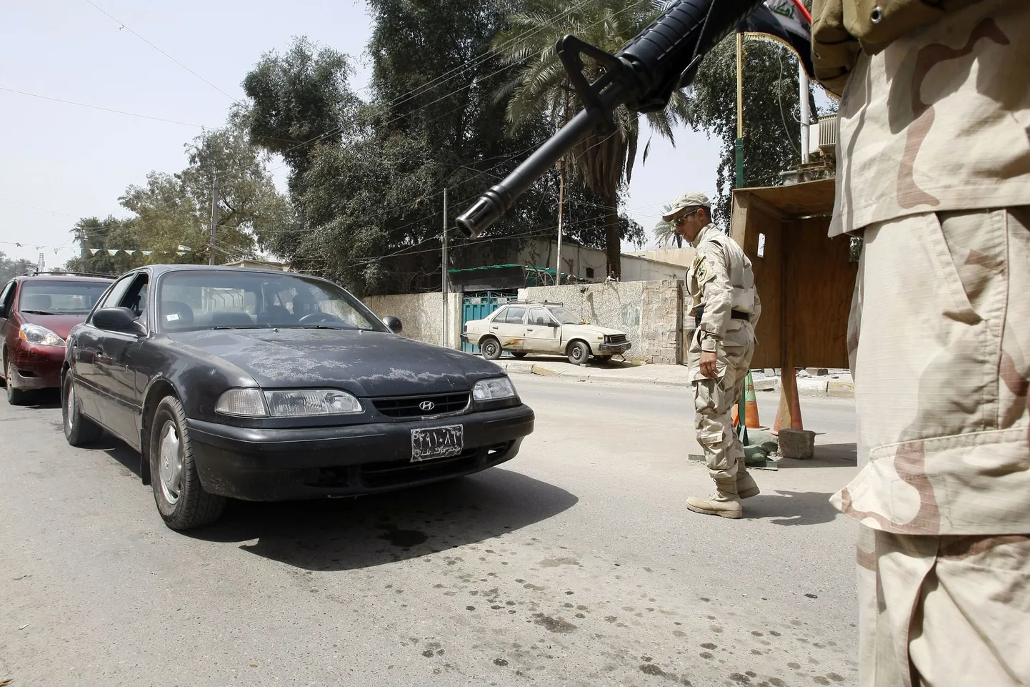 Солдаты в Ираке проверяют автомобили на пропускном пункте в Багдаде после учиненной боевиками кровавой расправы над мирными жителями.