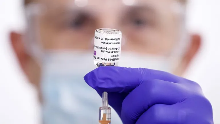 Мужчина держит в руках препарат вакцины AstraZeneca.