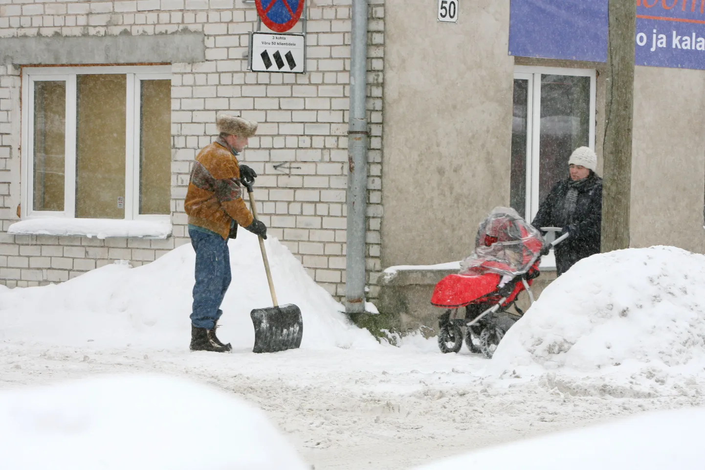 Suured lumevallid teede ääres. Lapsevankriga naine lumisel tänaval ja lumerookija.