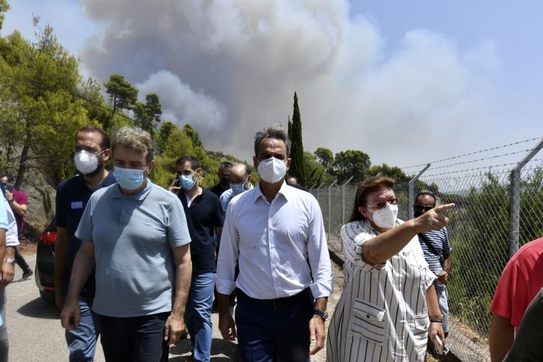 Greece's Prime Minister Kyriakos Mitsotakis, center, accompanied by Culture Minister Lina Mendoni, right, and Minister for Citizen Protection Michalis Chrisochoidis, left, visit the ancient Olympia during a wildfire in western Greece, Thursday, Aug. 5, 2021. Wildfires rekindled outside Athens and forced more evacuations around southern Greece Thursday as weather conditions worsened and firefighters in a round-the-clock battle stopped the flames just outside the birthplace of the ancient Olympics. (Giannis Spyrounis/ilialive.gr via AP)