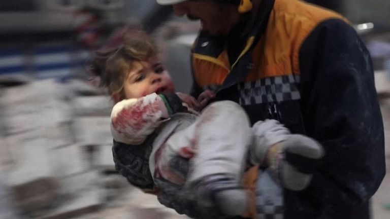 Спасатель в Сирии выносит из-под обломков здания уцелевшего ребенка