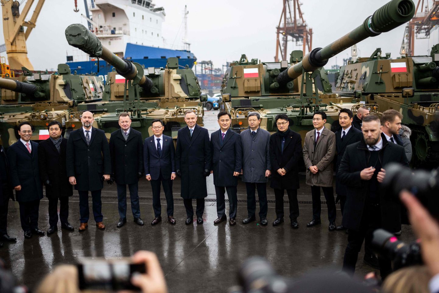 Poola president Andrzej Duda (vasakult kuues) ja kaitseminister Mariusz Blaszczak (vasakult neljas) poseerimas delegatsiooniga Soulist esimeste Lõuna-Korea lahingutankide üleandmise tseremoonial Gdynia konteineriterminalis 6. detsembril 2022.