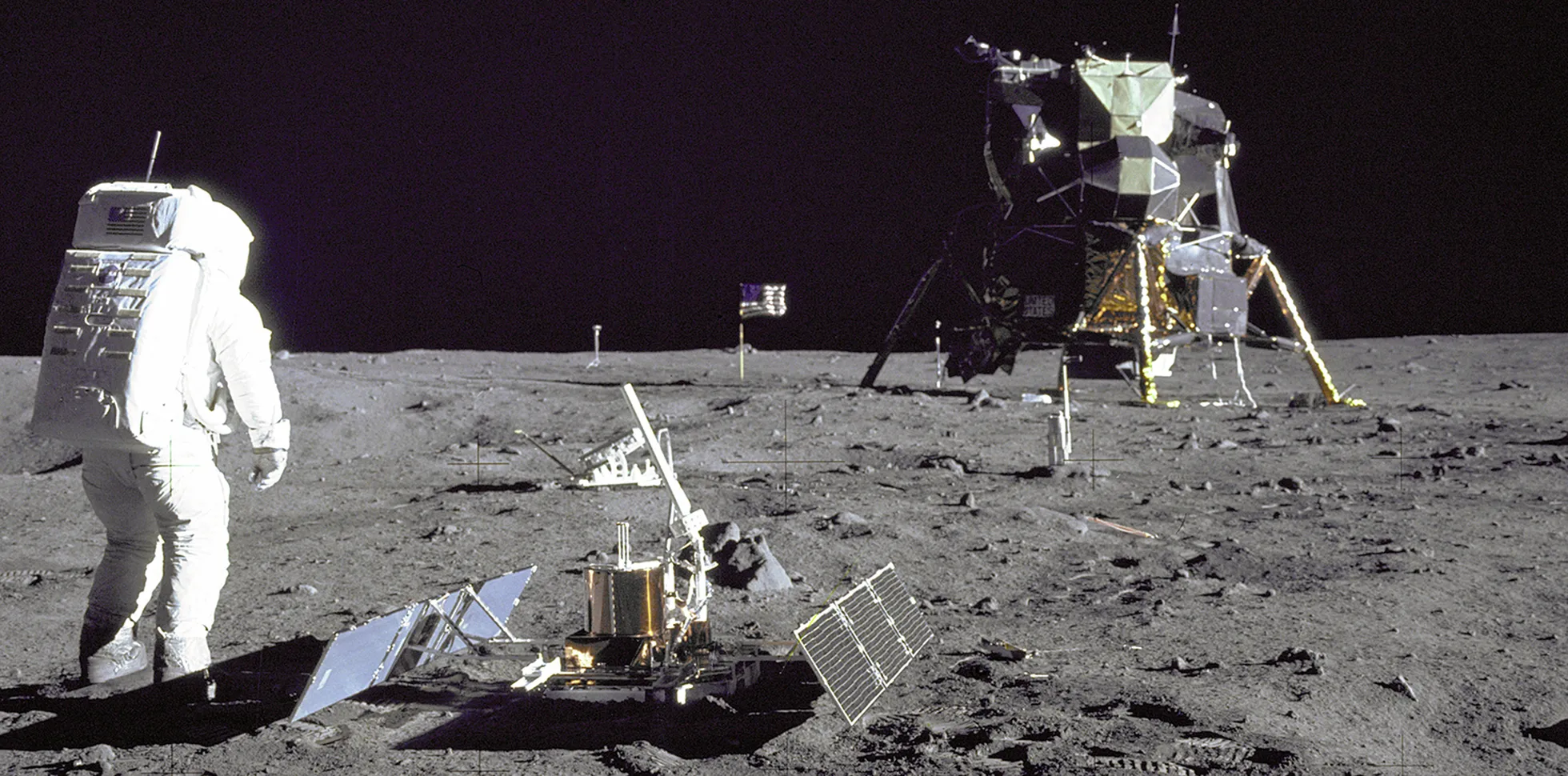 Buzz Aldrin seisab kuu seismomeetri kõrval. Taamal paistab kuumoodul.