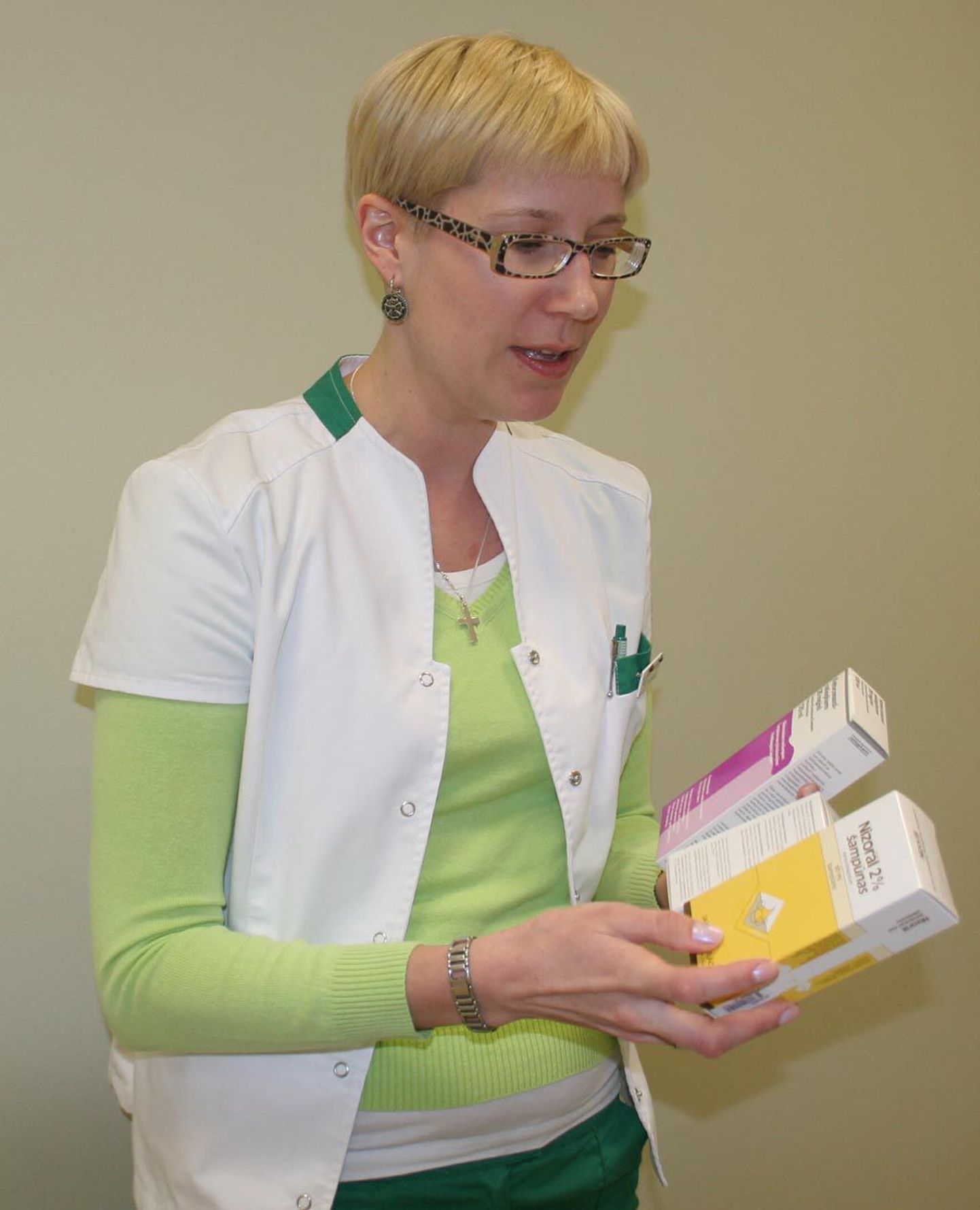Ülikooli apteegi juhataja Karin Alamaa-Aas näitab kolme firma kõõmaravišampoone.