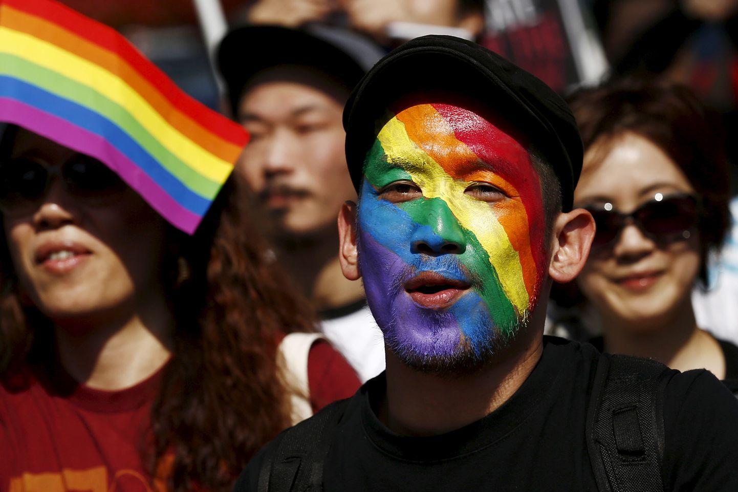 Мужчина, чье лицо раскрашено в цвета радуги, принимает участие в параде Tokyo Rainbow Pride в Токио.