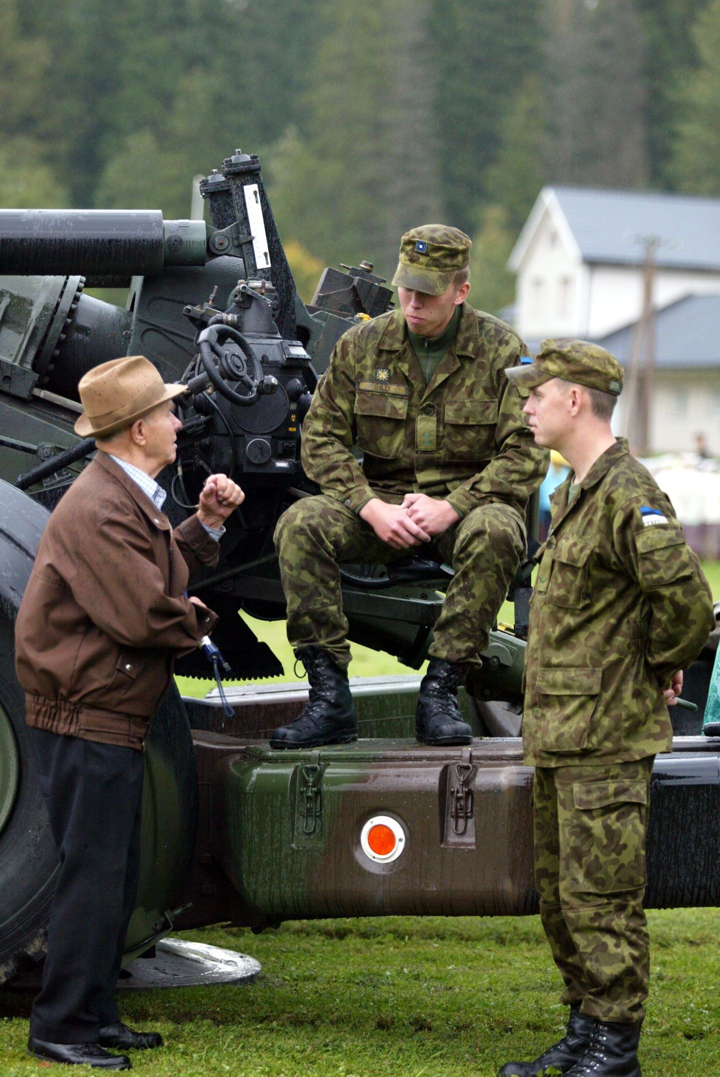 Kirde kaitseringkonna nooremleitnant Reimo Sild (istub) ja nooremveebel Virkko Parts tutvustavad vanale rindemehele Karl Allmannile Porkuni lahinguväljal välihaubitsat FH 70.