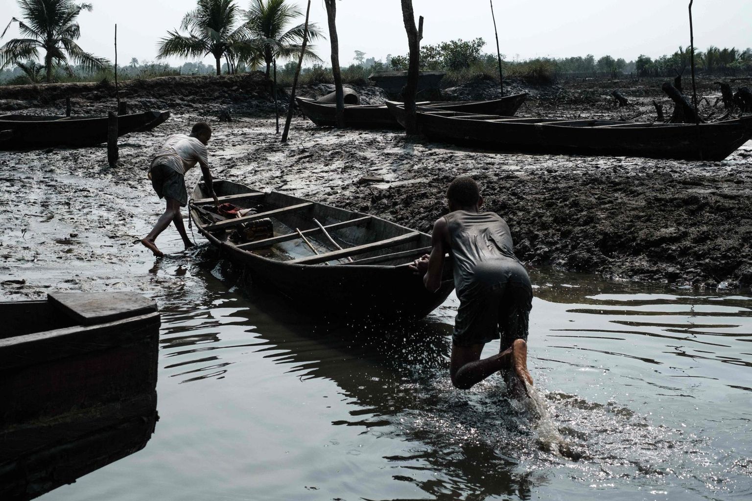 Kalamehed lükkavad paati õliseguses mudas mõõna ajal K-Dere külas ogoni hõimu põlistel aladel Nigeri jõe deltas.