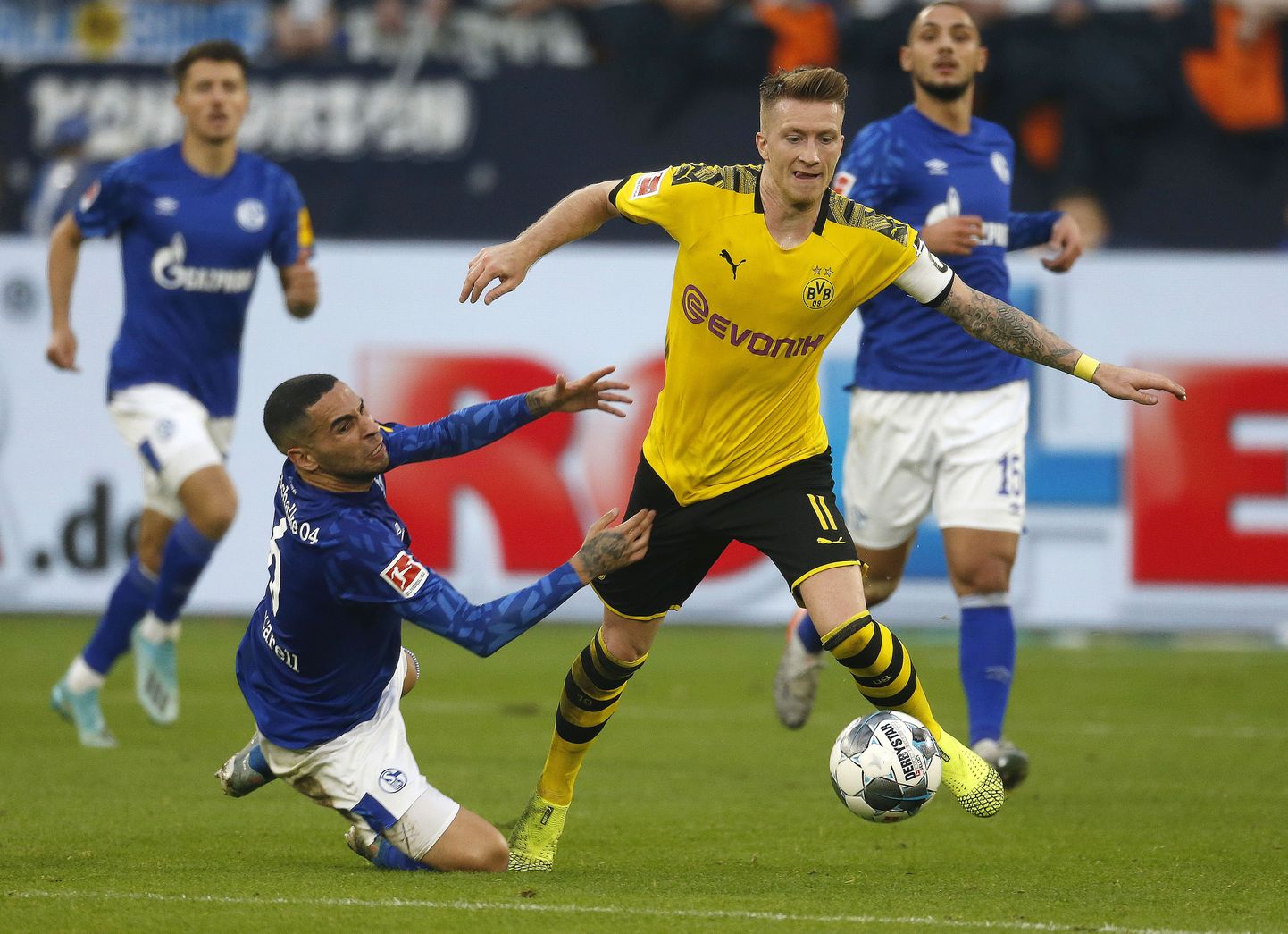 Dortmundi pallur Marco Reus proovib Schalke kaitsjate eest põgeneda.