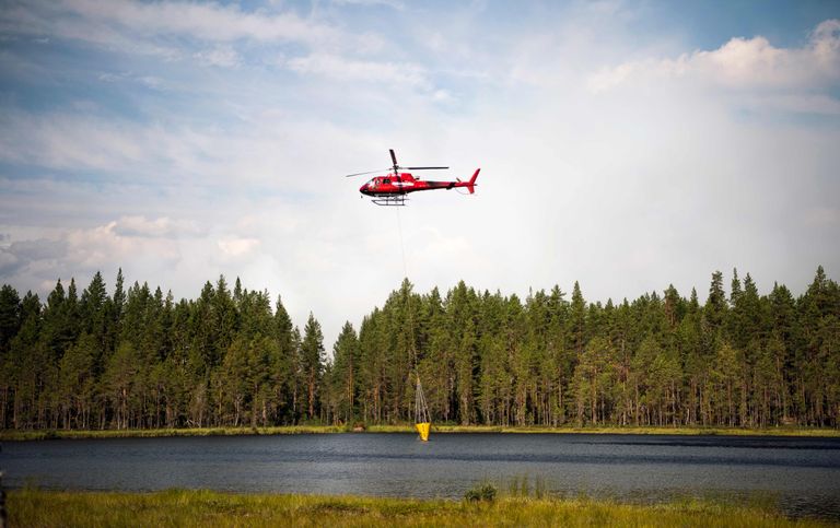 Tuletõrjujad täidavad kustutuskopterit veega kohalikust järvest Korskrogenis Ljusdali lähedal. 
